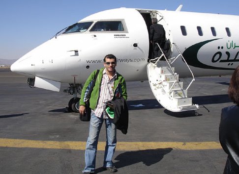 Cheb Ali poses in front of the specially chartered plane that will take them from Sanaa to Sayum